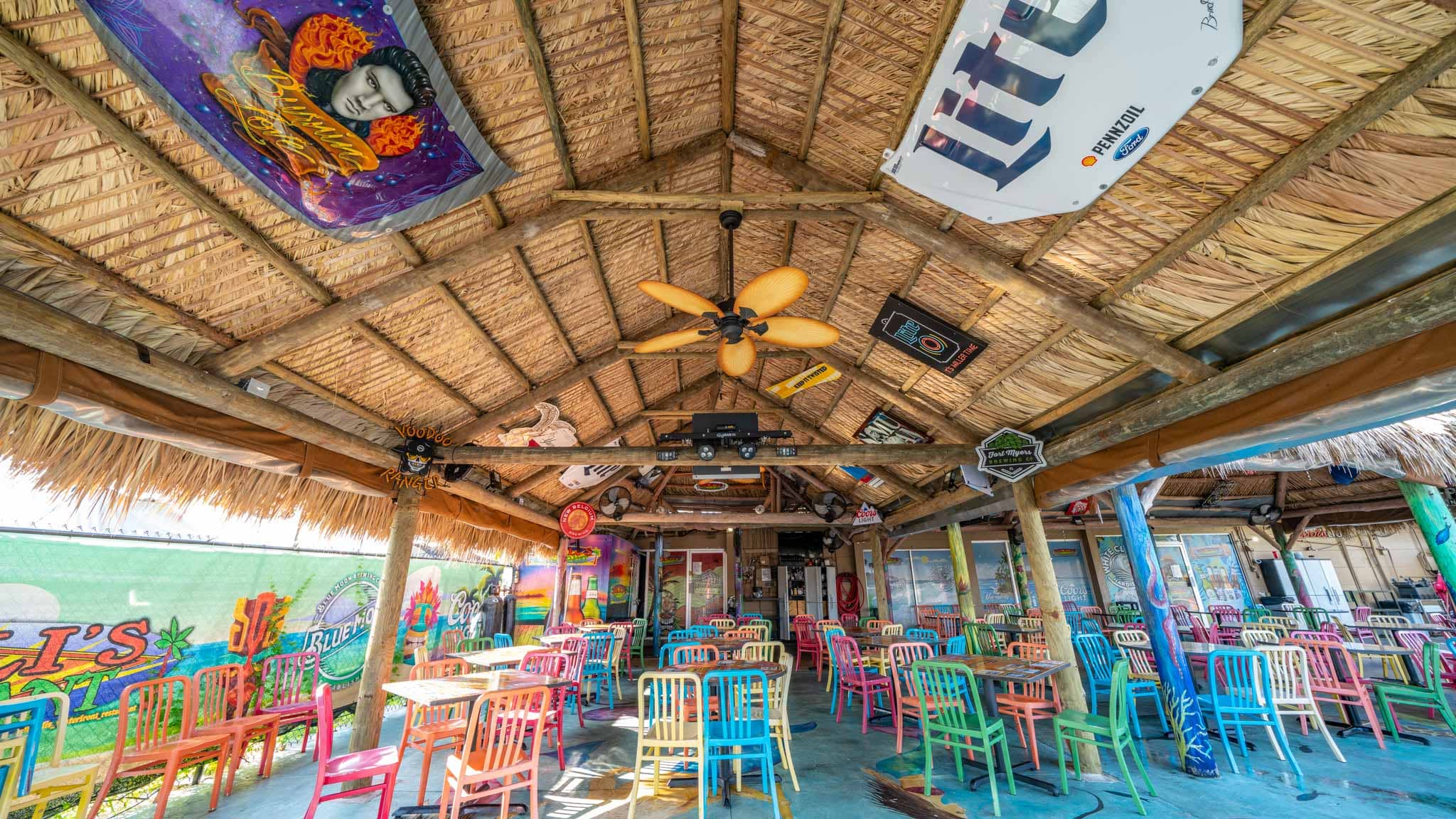 Tiki hut with decorated interior built over seating outside waterfront restaurant